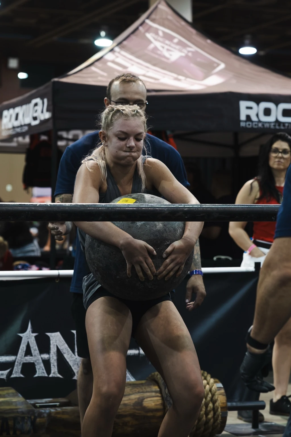 Strongwoman athlete carrying an Atlas stone during competition